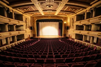 Vue panoramique de la salle du Grand Rex avec rangées de sièges en velours bordeaux et décor Art Déco doré avant un concert